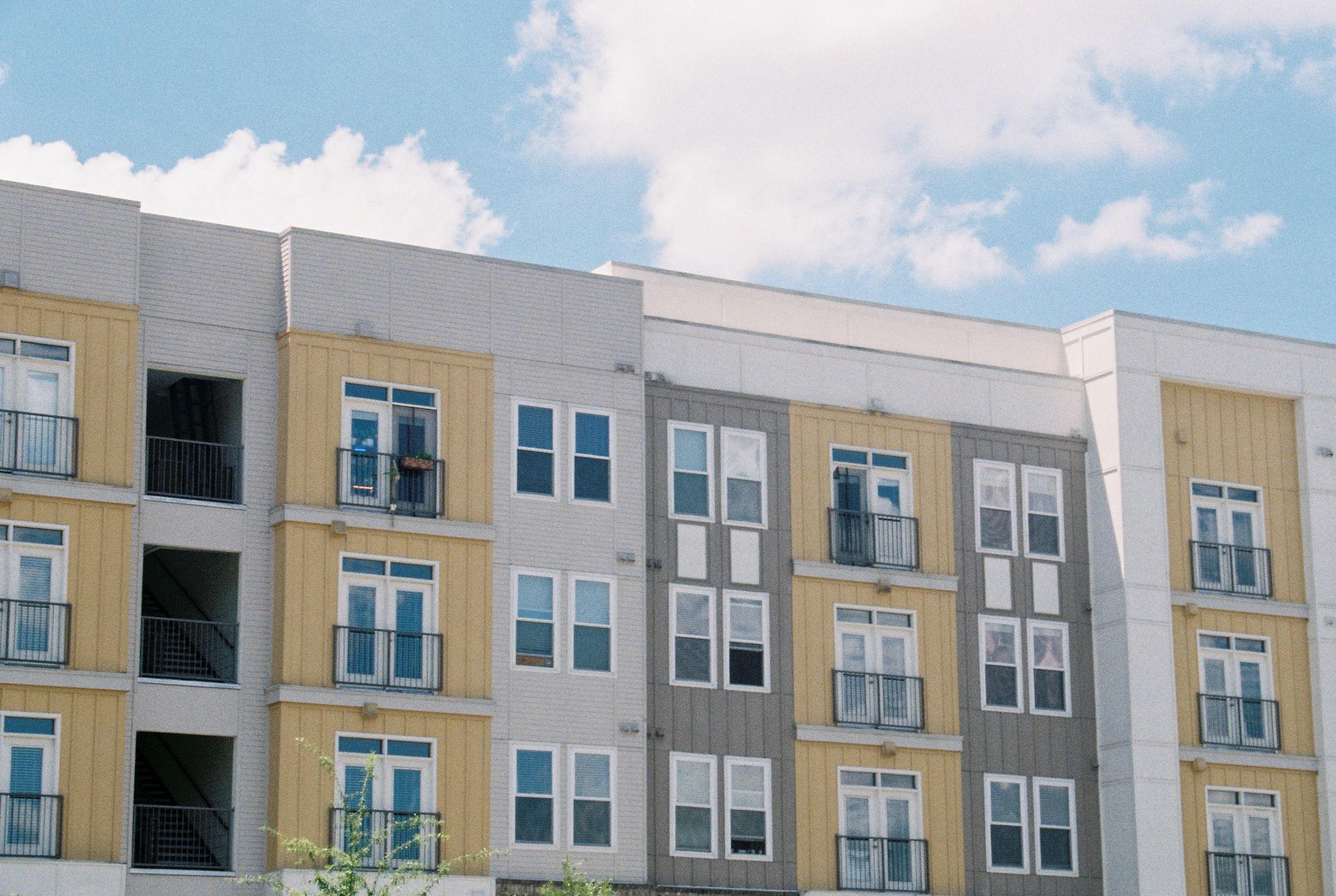 Contemporary apartment building exterior with yellow and grey panels under a clear blue sky