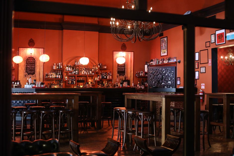 Warmly lit bar interior with wooden furniture and chandeliers