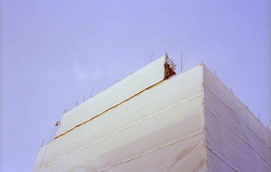 Building under renovation wrapped in protective material with visible scaffolding