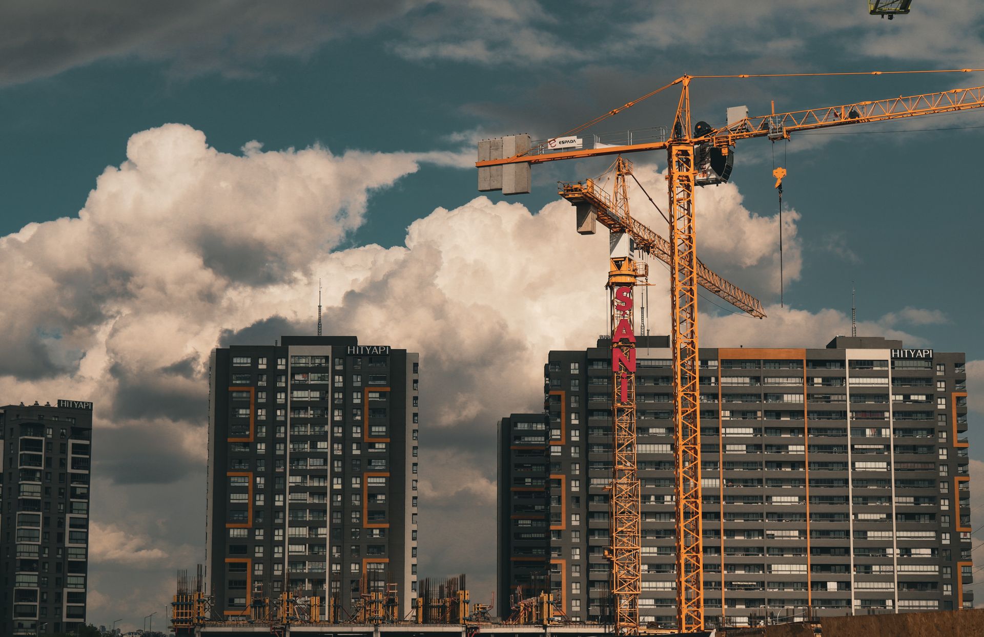 Construction site with cranes and buildings under a dramatic cloudy sky