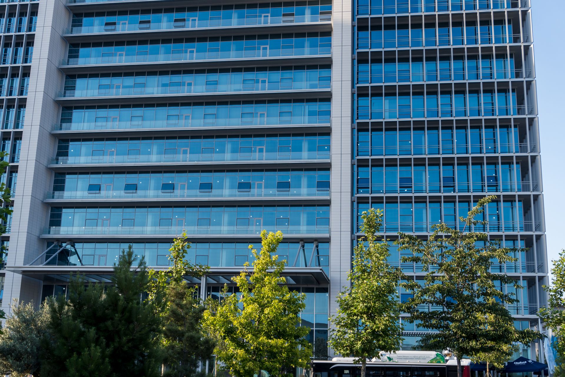 Glass facade skyscraper with trees in downtown urban scene