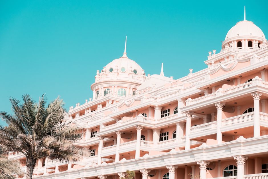 Captivating view of an elegant and luxurious hotel facade with palm trees under a clear blue sky
